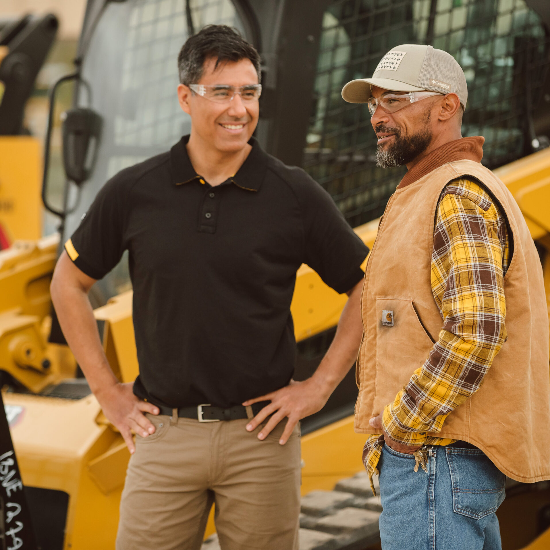 A salesman and a customer standing in front of a lineup of Cat equipment
