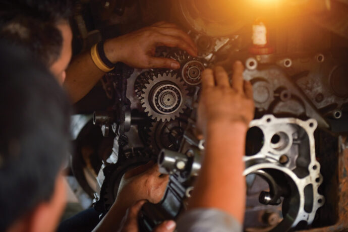 Closeup of two people working on gears in an AGCO machine