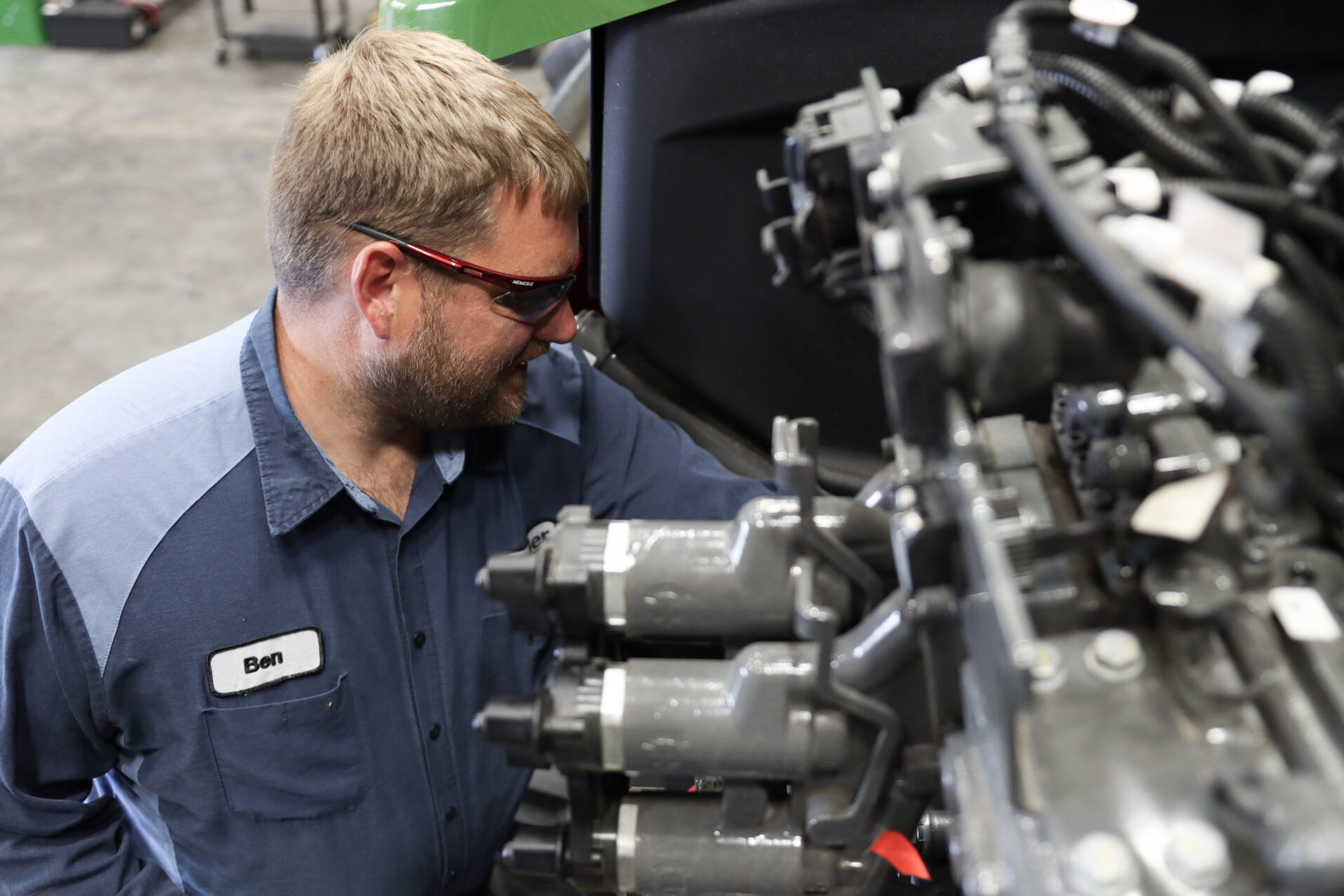 Technician look at equipment, next to large machinery.