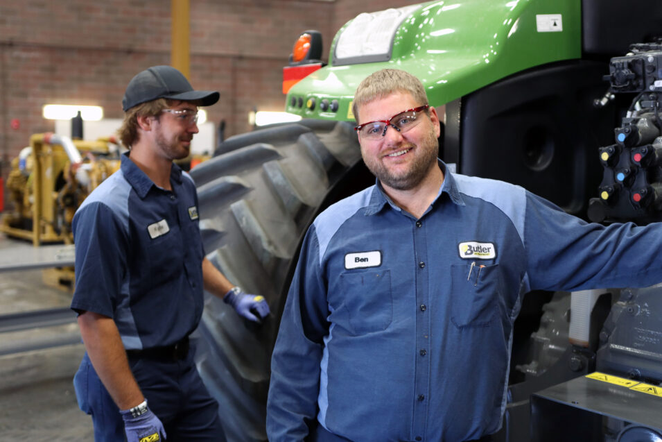 Two technicians next to equipment, one looking at the camera smiling.