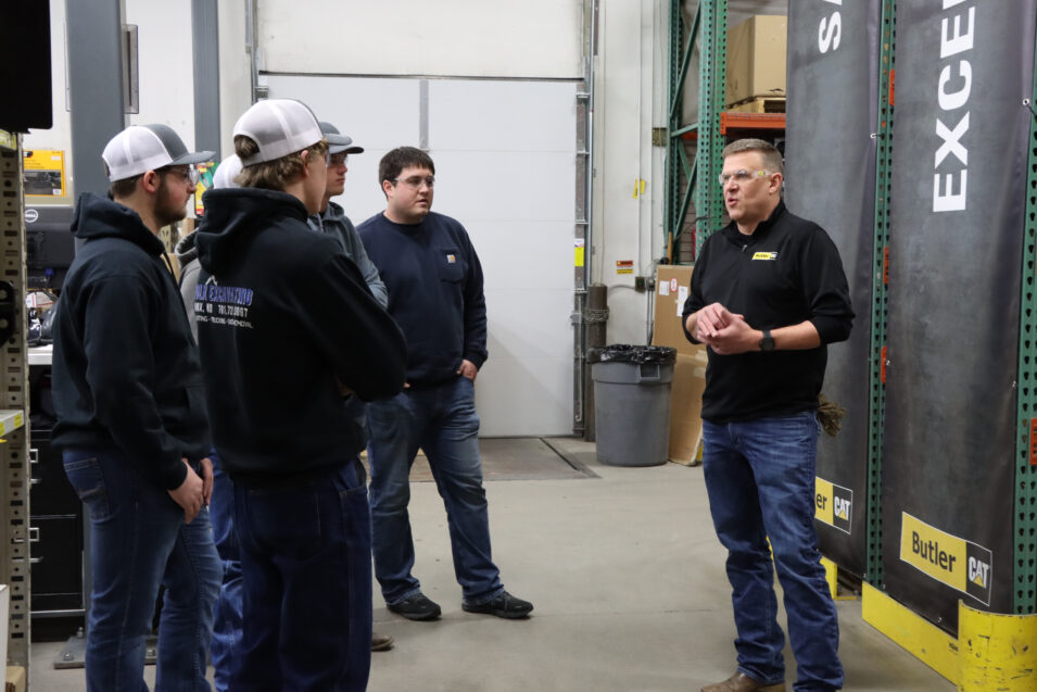 Small group of students looking at an instructor in a warehouse.