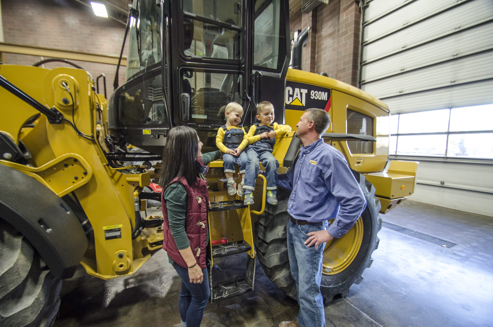 Two parents next to twins sitting on a CAT 930M.