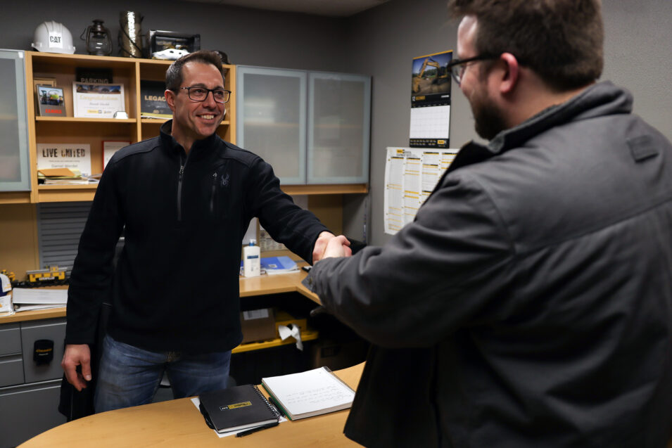 Two men in an office shaking hands.