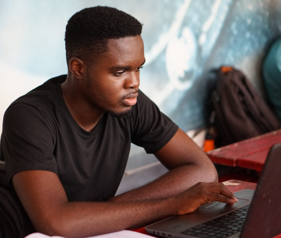 Man looking at laptop with hand on trackpad.